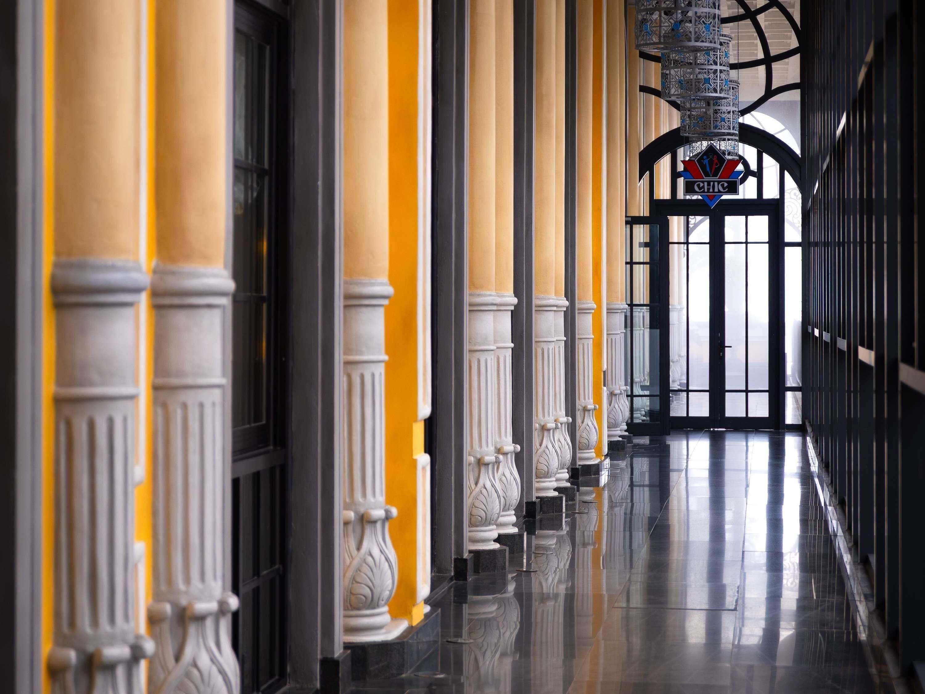 A corridor with columns, a reflective floor, and a sign with 'CHIC' on it.