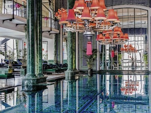 A spacious lobby with a central reflective pool, multiple seating areas, and a grand staircase.