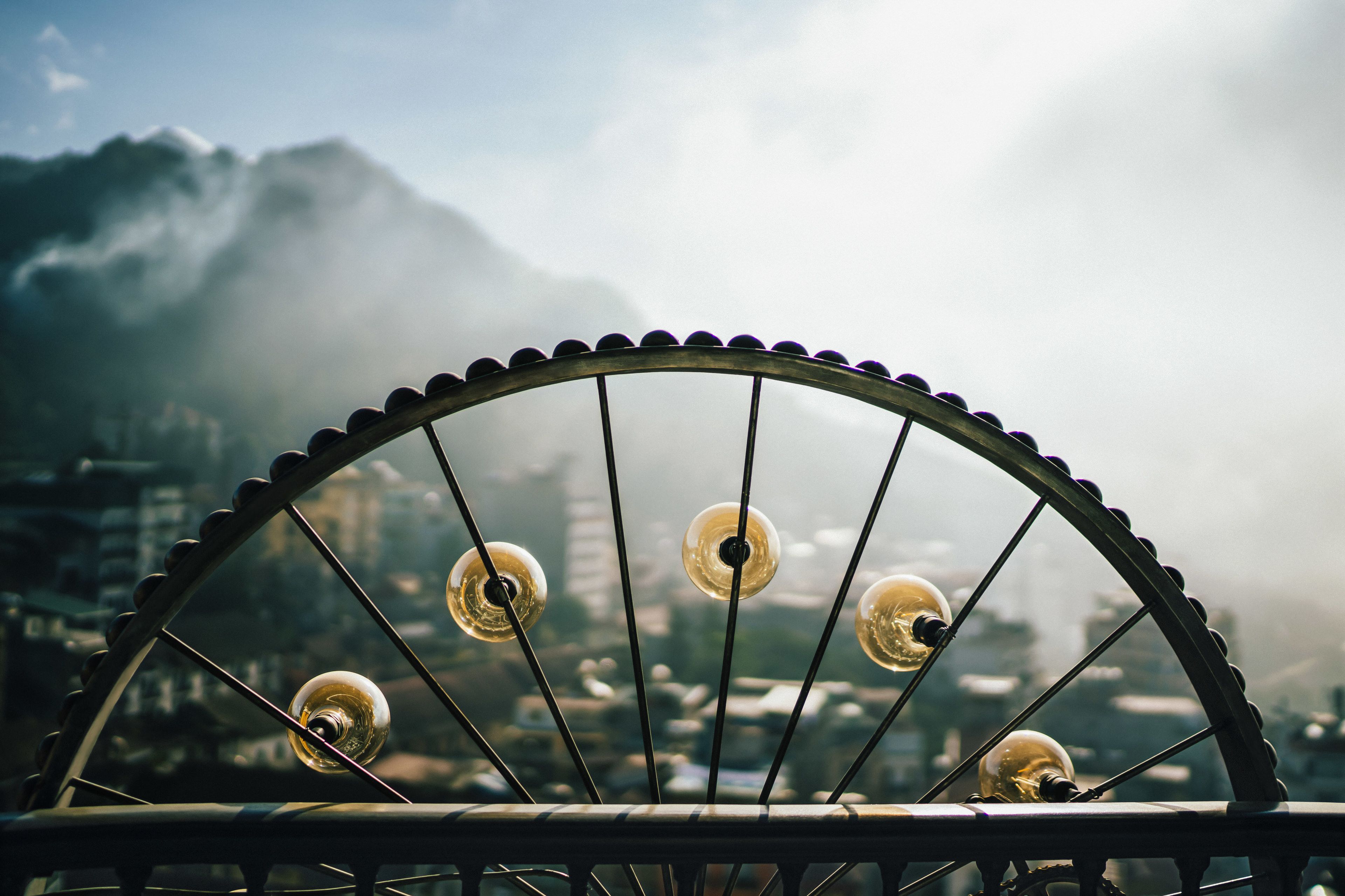 A Ferris wheel with lights against a cityscape and mountains in the background.