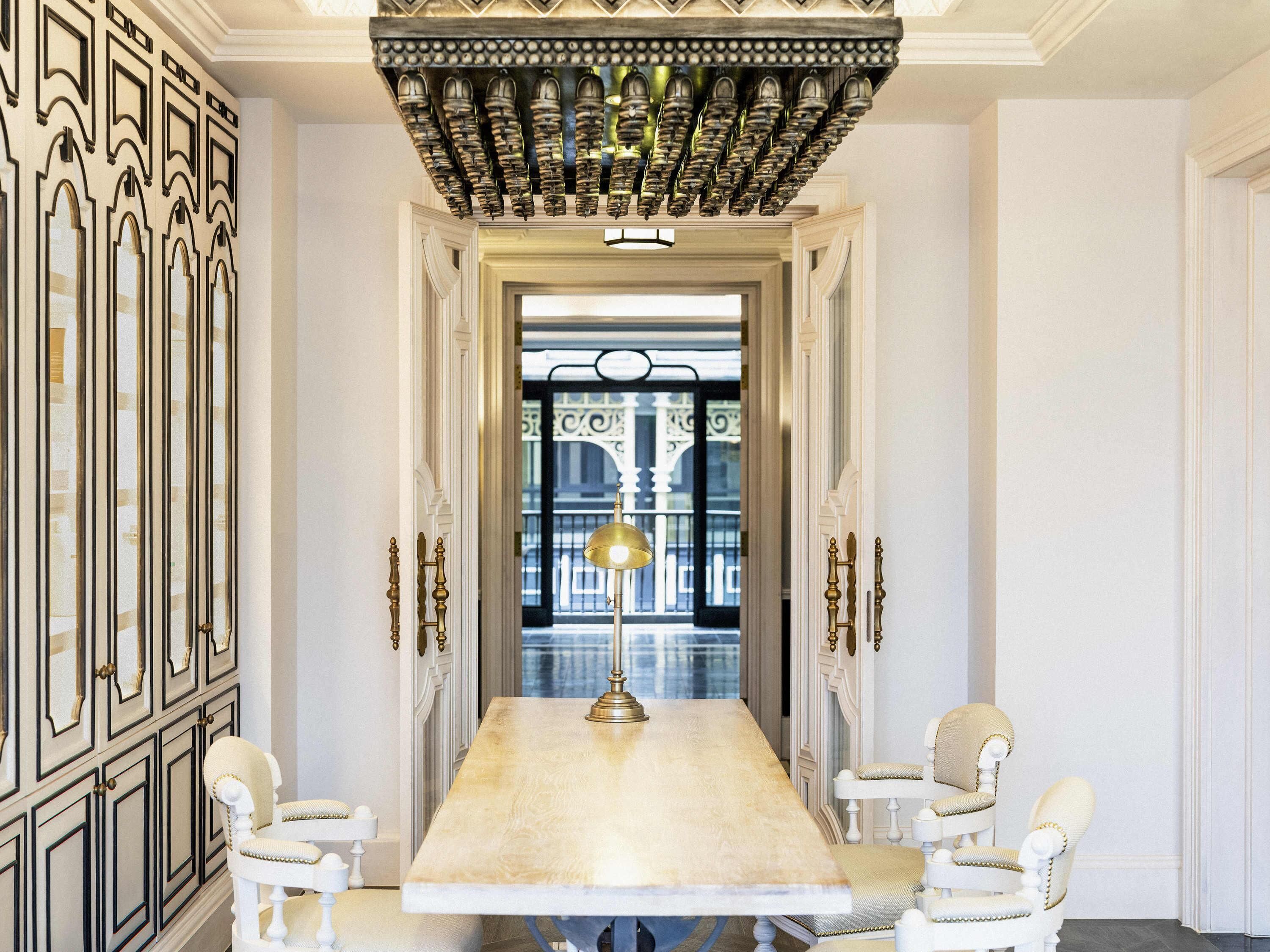 Une salle à manger élégante, avec une longue table, des chaises richement décorées et un plafond orné.