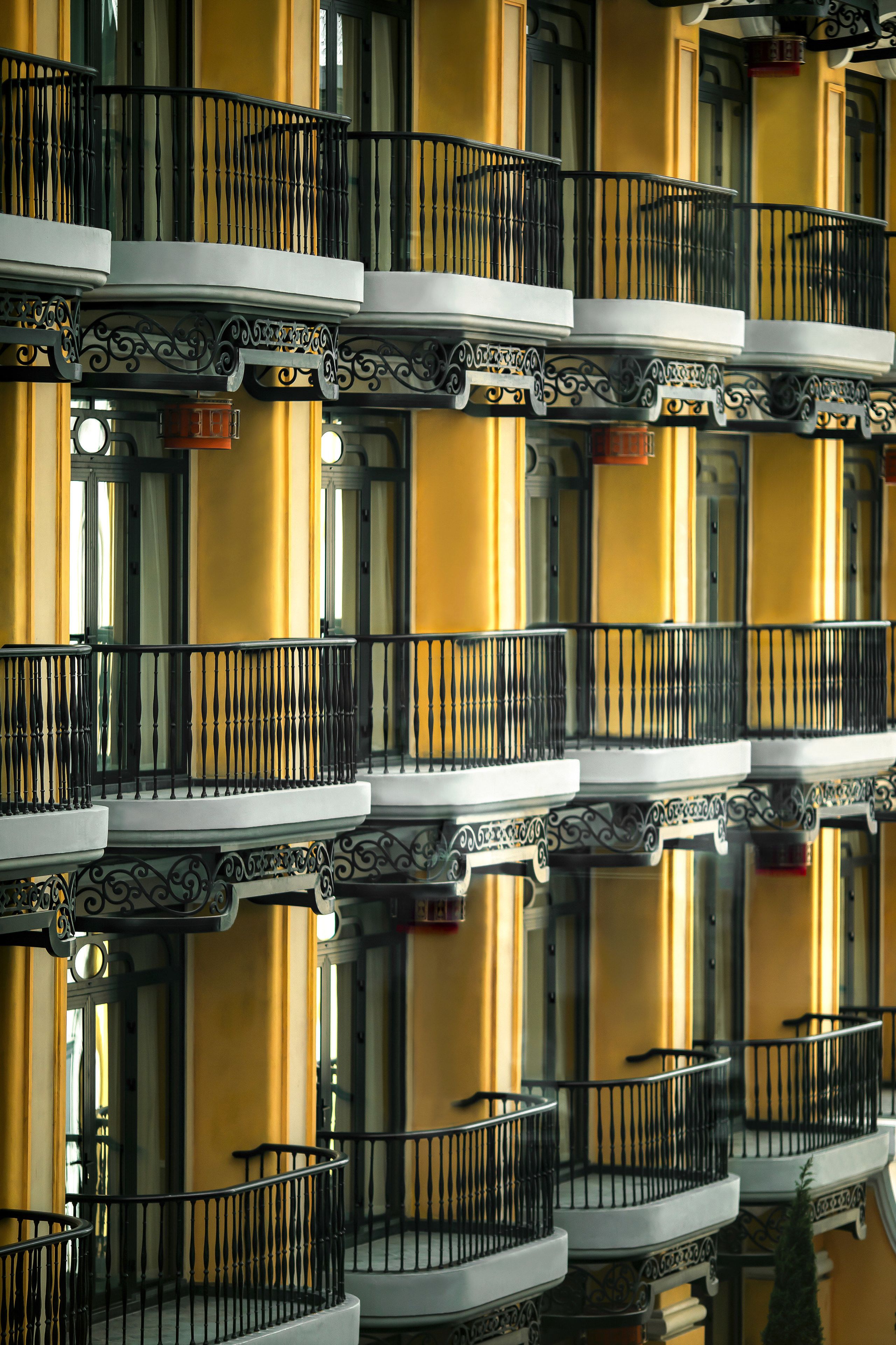 A building with multiple balconies, each with ornate black railings and white columns.