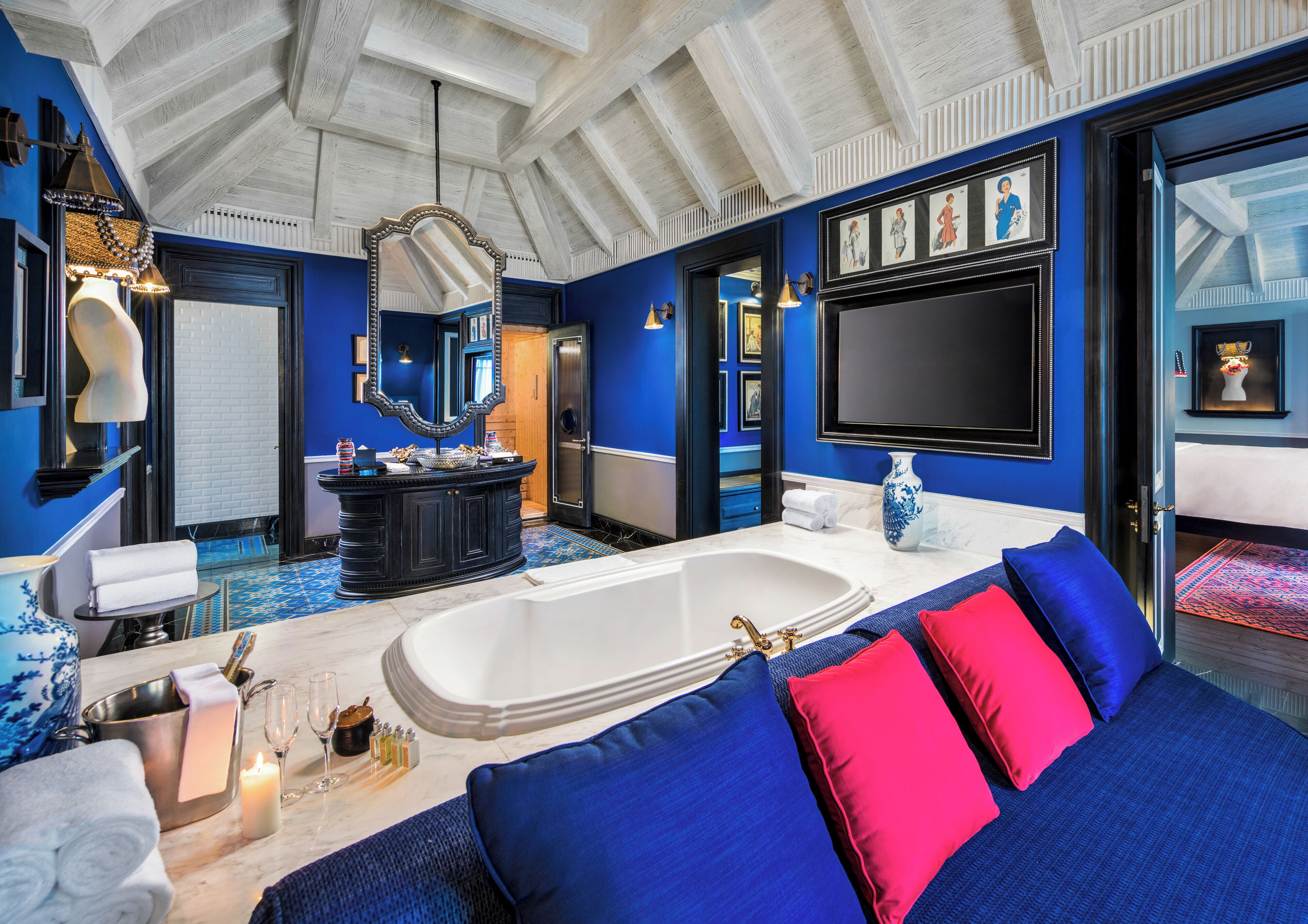 Une salle de bain luxueuse avec une grande baignoire, un meuble-lavabo avec un miroir et une décoration aux couleurs bleue et rouge.