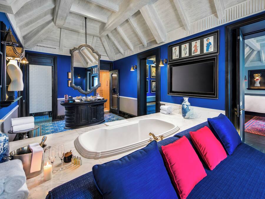 Une salle de bain luxueuse avec une grande baignoire, un meuble-lavabo avec un miroir et une décoration aux couleurs bleue et rouge.