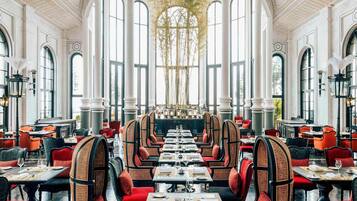 Un comedor espacioso con techos altos, ventanas amplias y candelabros ornamentados.