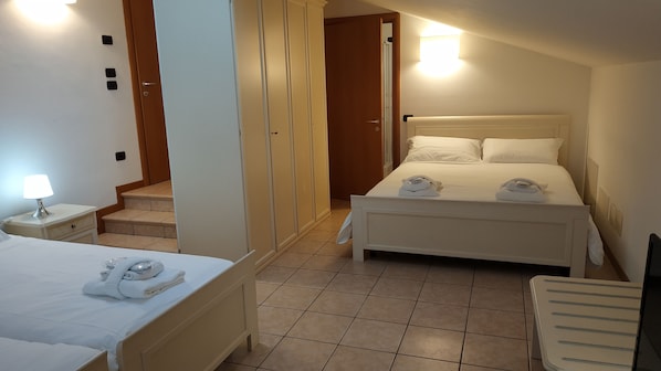 A hotel room with a bed, a nightstand, a lamp, a wardrobe, and a bathroom with a shower.