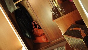 Um guarda-roupa de madeira com espelho, uma garrafa de álcool e um vaso com rosas vermelhas.