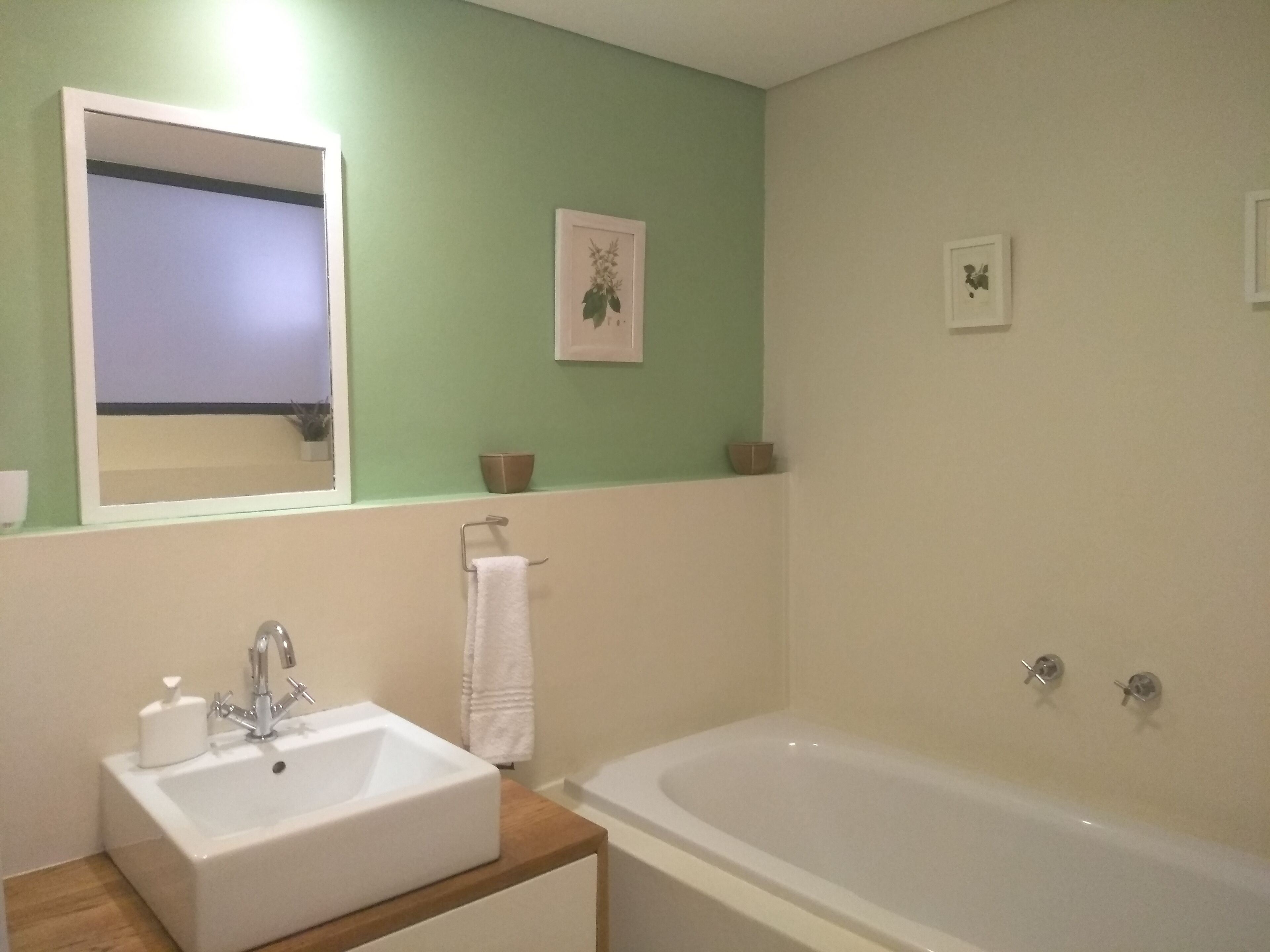 A bathroom with a sink, mirror, and bathtub.