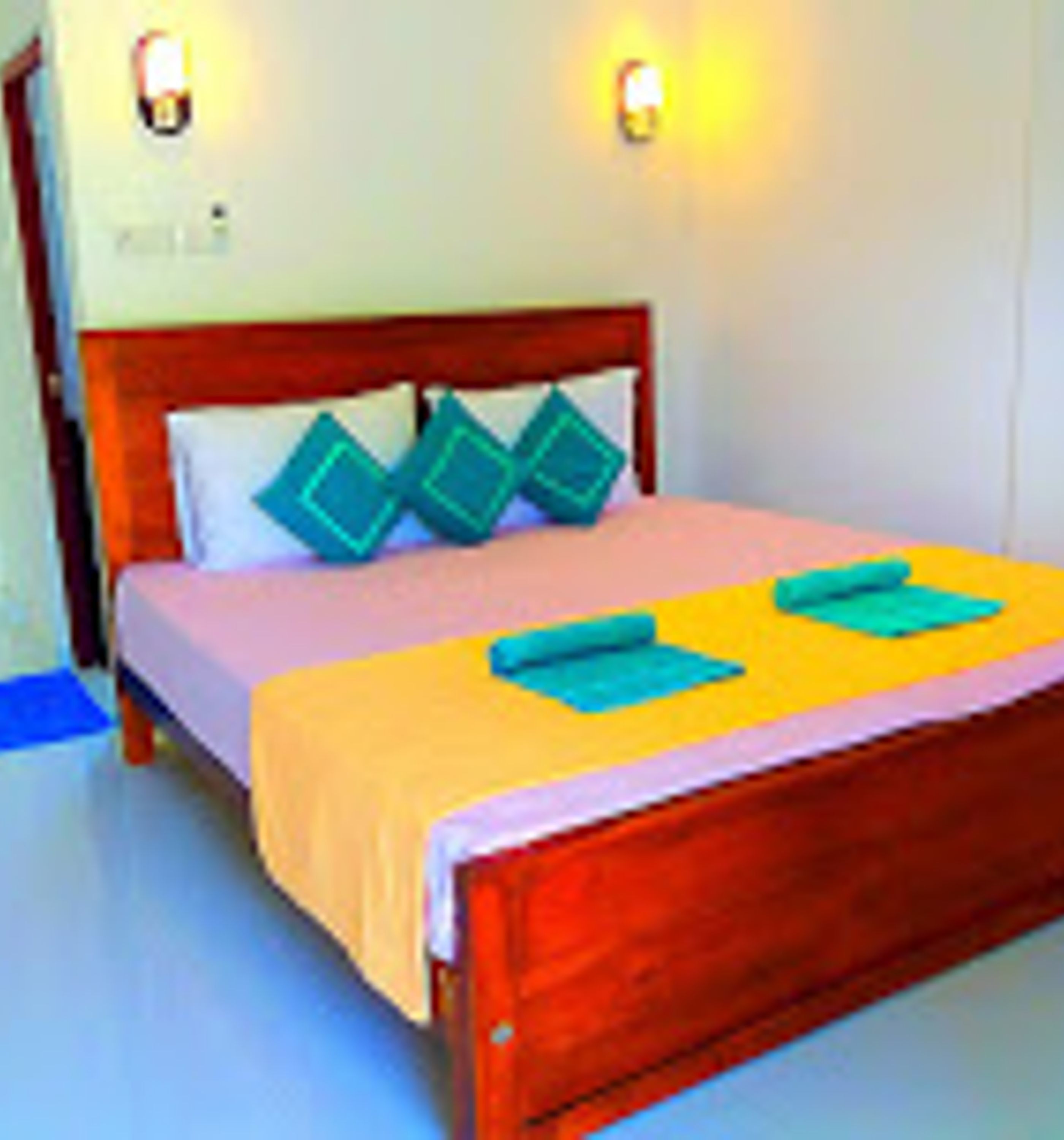 Una cama con estructura de madera, una colcha amarilla y dos almohadas.