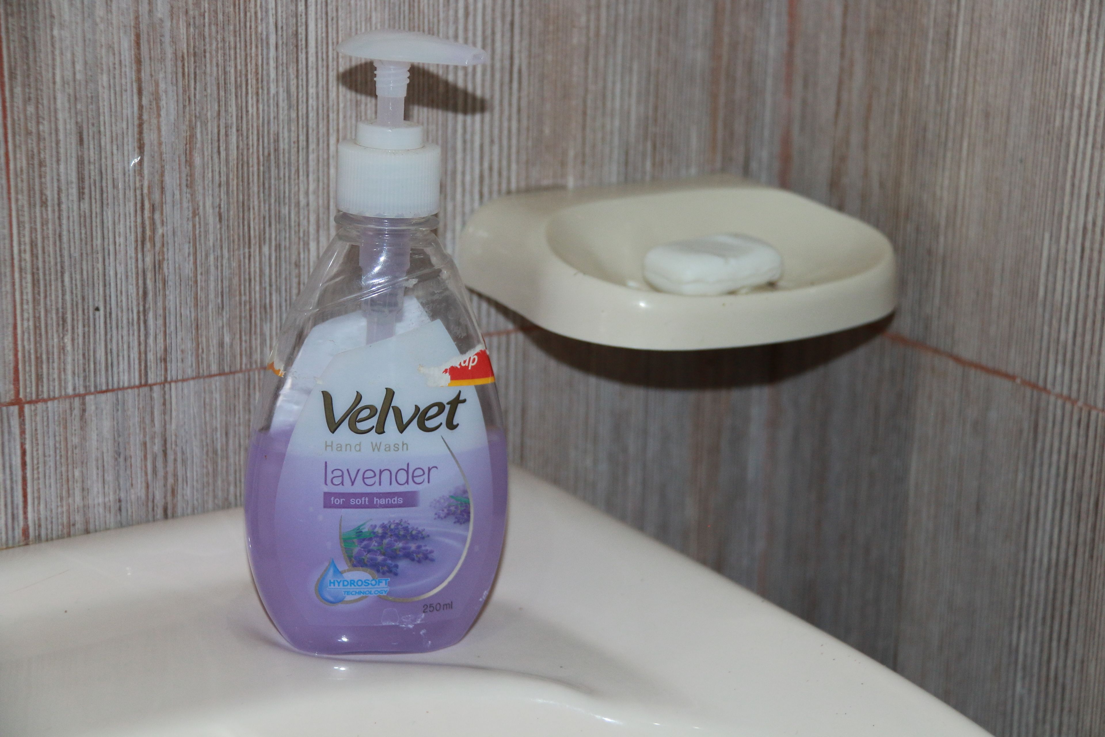 A bottle of Velvet hand wash soap on a bathroom sink.