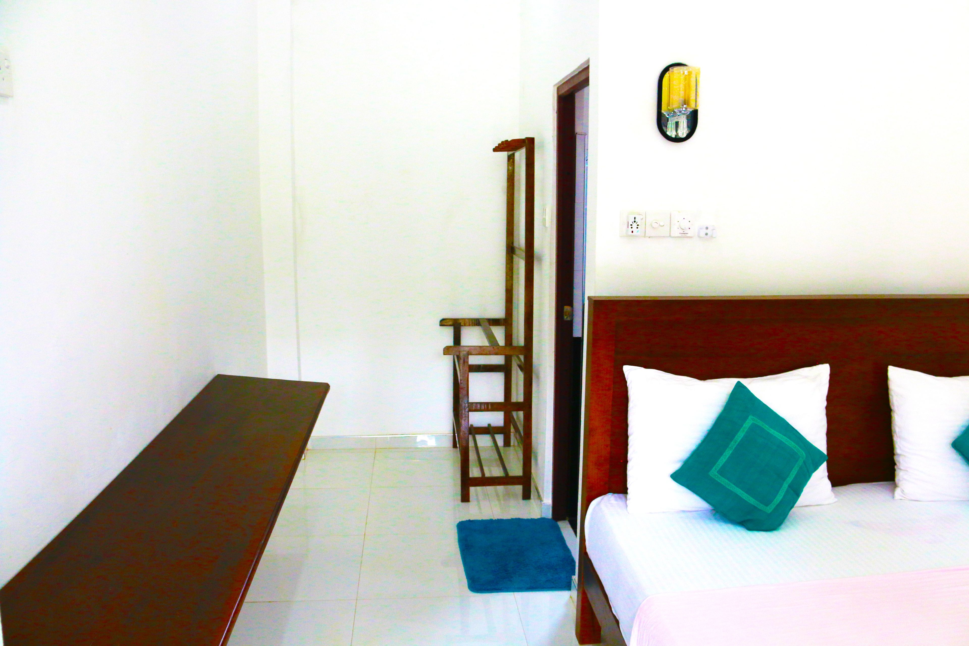 A bedroom with a bed, a wooden chair, a blue rug, and a nightstand.
