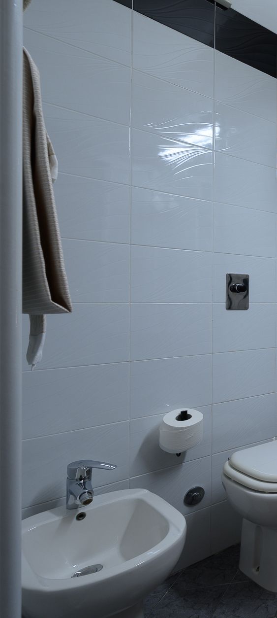 Un baño con lavamanos blanco, inodoro y una toalla colgada en la pared.