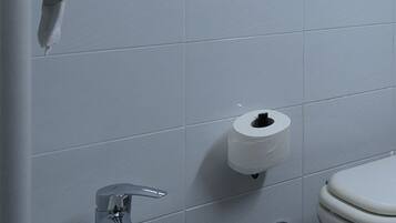 Un baño con lavamanos blanco, inodoro y una toalla colgada en la pared.