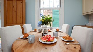 Ein Esstisch mit Frühstücksangeboten, einer Kaffeemaschine und einem Blumenstrauß.
