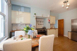 Una cocina moderna con armarios blancos, una mesa de comedor de madera y diversas opciones para el desayuno.