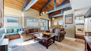 A spacious living room with a large sectional sofa, a coffee table, and a kitchen area with a microwave and oven. - Bigwood 62 Quiet and Cozy in Forest Setting, with Garage Parking by RedAwning (Mammoth Lakes)