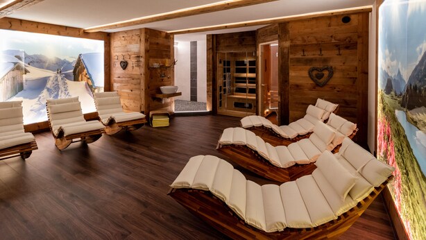 A spa room with wooden walls, a large window with a snowy mountain view, and multiple massage chairs. - Fetz Luxury Appartements (Steeg)