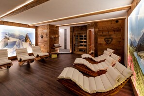 A spa room with wooden walls, a large window with a snowy mountain view, and multiple massage chairs. - Fetz Luxury Appartements (Steeg)