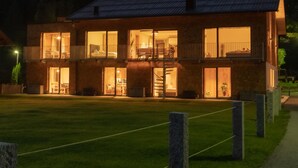A two-story building with multiple windows and balconies, surrounded by a well-maintained lawn and stone pillars. - Fetz Luxury Appartements (Steeg)