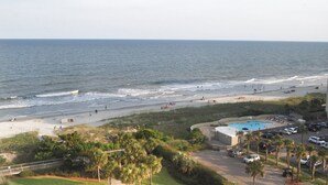 A beach view with a swimming pool and parking area.