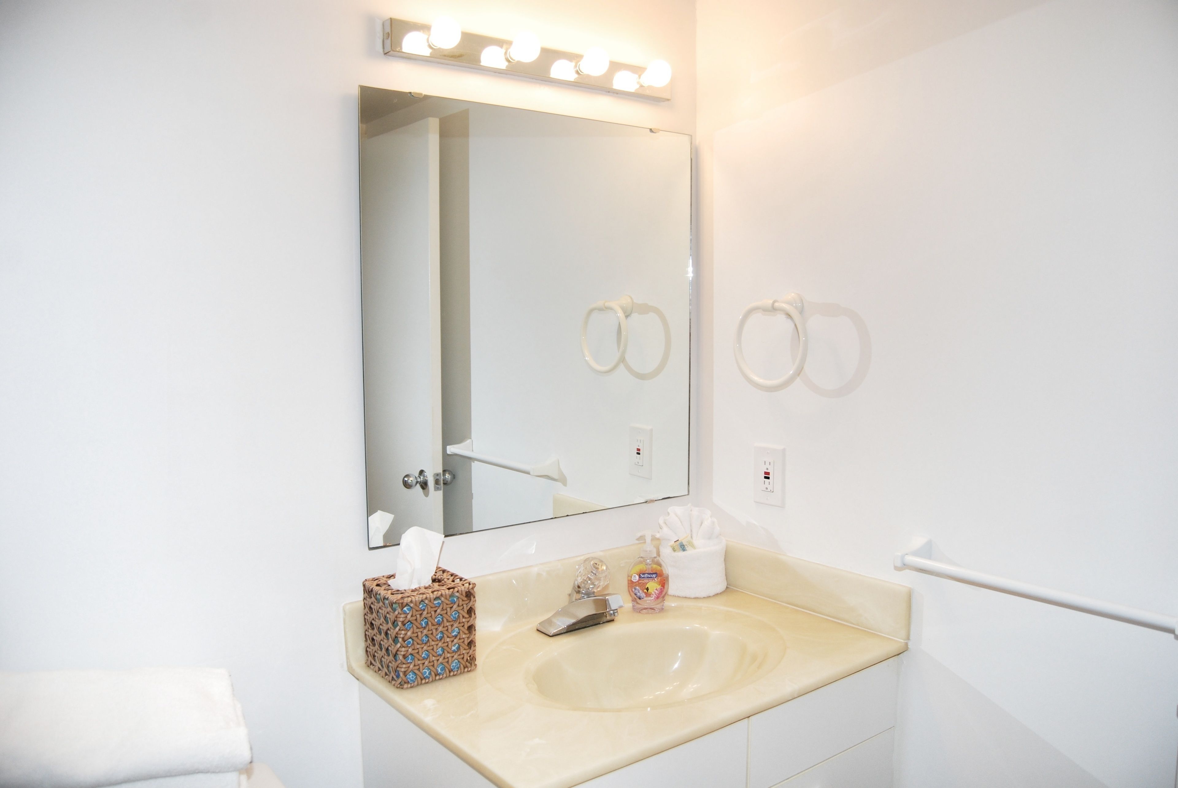 A bathroom with a large mirror, a sink, and a towel rack.