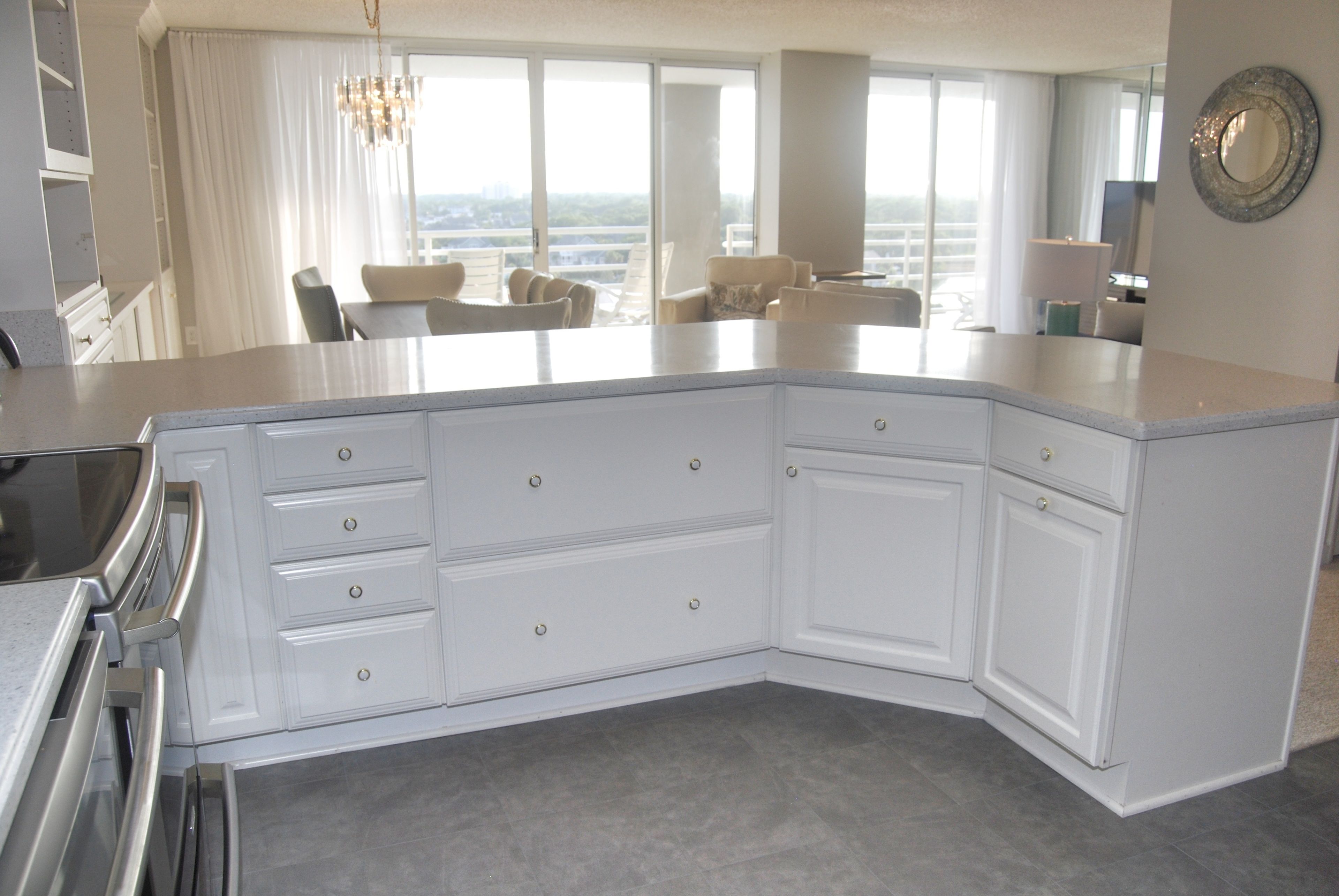 Een moderne keuken met witte kastjes, een inbouwoven en een groot kookeiland met aanrecht.