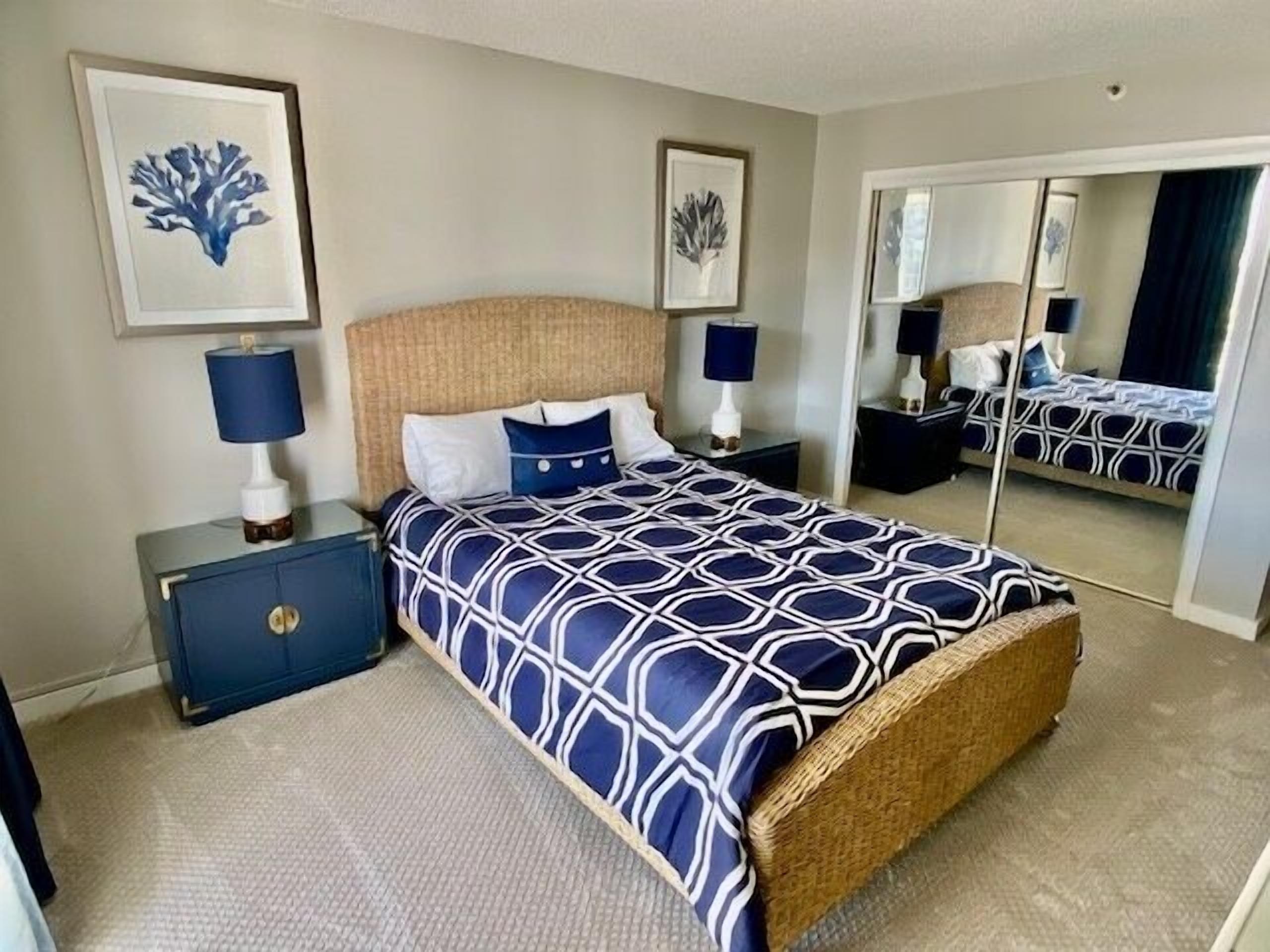 Un dormitorio con cama, mesitas de noche, cómoda y un espejo grande.