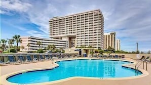 A hotel with a large pool, multiple balconies, and a modern design.