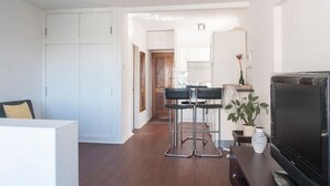 Una sala de estar moderna con un sofá, televisor y una zona de comedor con sillas y mesa.