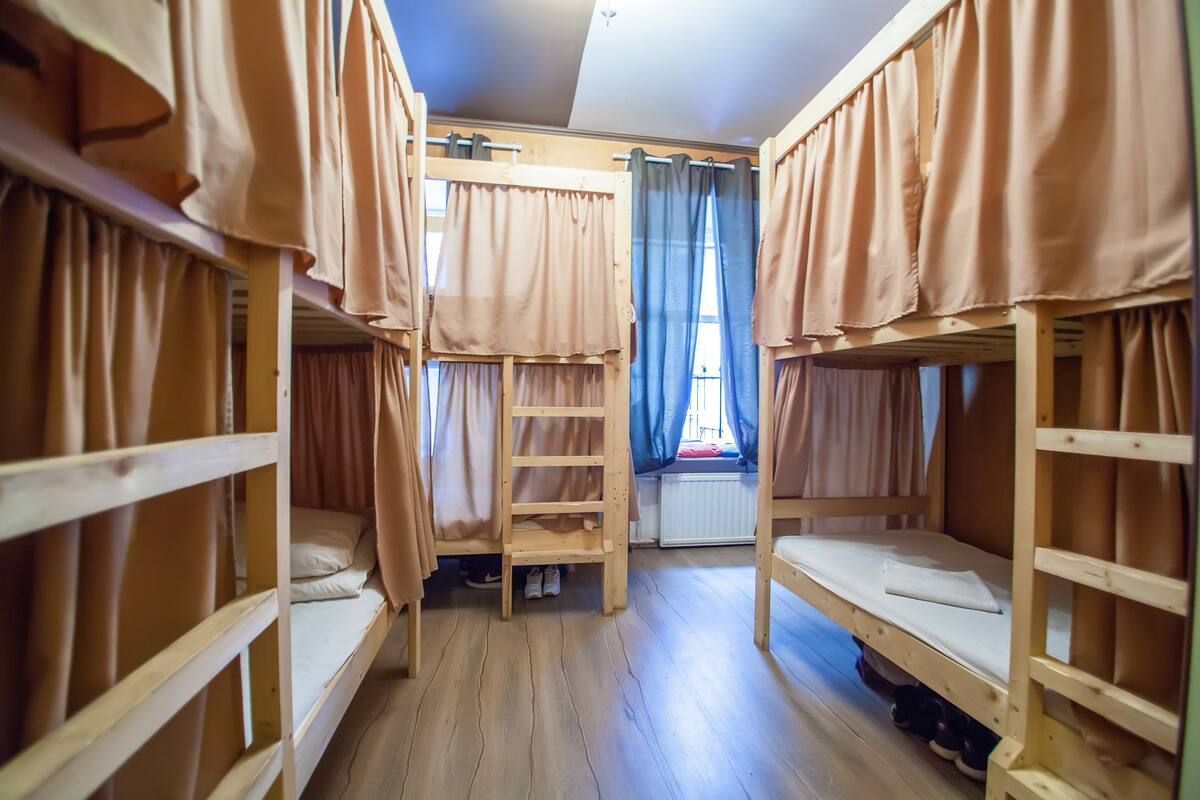 Une chambre de dortoir avec des lits superposés, une échelle et des rideaux.