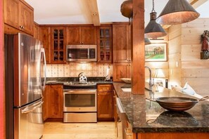 A modern kitchen with wooden cabinets, stainless steel appliances, and a granite countertop. - House Steps to Gondola and Vail Village by RedAwning (Vail)
