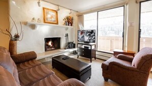A living room with a fireplace, a television, and a sofa. - Condos with Ski Locker and Vail Mountain Views by RedAwning (Vail)