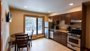 A modern kitchen with wooden cabinets, a stainless steel refrigerator, a microwave, a coffee maker, and a double oven. - Spacious Condo with Outdoor Heated Pool and Hot Tubs by RedAwning (Vail)