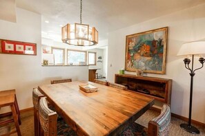 Enjoy meals in this elegant dining area with a large table and comfortable chairs, a beautiful painting above, and a stylish chandelier.