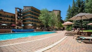 Ein Hotel mit Schwimmbad, Liegestühlen und Sonnenschirmen.