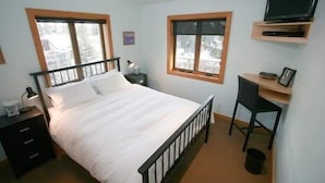 A bedroom with a bed, a desk, a chair, a TV, and a window. - Condo 100 Yards to Gondola One by RedAwning (Vail)