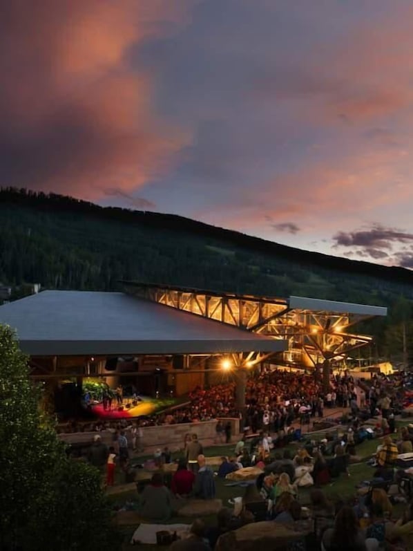 A large outdoor amphitheater with a modern design, surrounded by a crowd of people.
