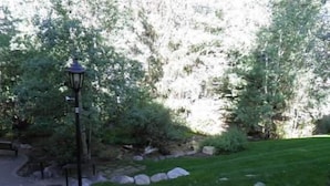 A garden pathway with a lamp post, surrounded by lush greenery and a well-maintained lawn. - Condo 100 Yards to Gondola One by RedAwning (Vail)