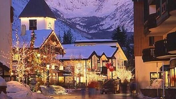A snow-covered street with buildings, including a lodge with a conical roof and a restaurant with outdoor seating. - Condo 100 Yards to Gondola One by RedAwning (Vail)