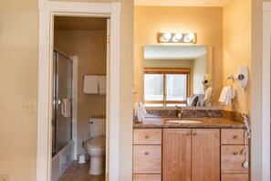 A bathroom with a shower, toilet, vanity with a mirror, and a window. - Condo with Pool & Hot Tubs, Free Shuttle by RedAwning (Vail)