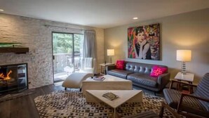 Uma sala de estar moderna com lareira, um sofá, uma mesa de centro e um quadro grande na parede.