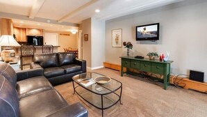 A modern living room with a leather sofa, a glass coffee table, and a green cabinet. - Condo with Outdoor Heated Pool and Free WiFi by RedAwning (Vail)