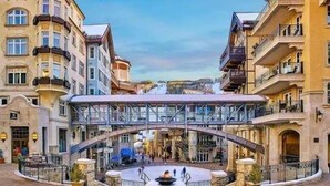 Un patio de hotel con un puente de cristal, una fuente y vistas de la ciudad.