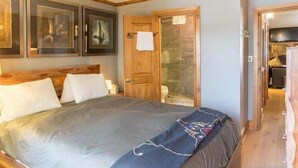 Un dormitorio con cama, puerta de madera y espejo.