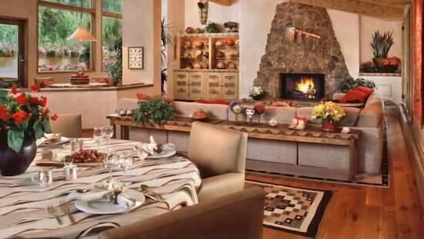 A cozy living room with a stone fireplace, a dining area with a table set for four, and a large window overlooking greenery. - Penthouse with Panoramic Views of Vail Mountain and the Gore Range by RedAwning (Vail)