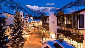 A snow-covered street with traditional buildings, a Christmas tree, and mountains in the background. - Penthouse with Panoramic Views of Vail Mountain and the Gore Range by RedAwning (Vail)