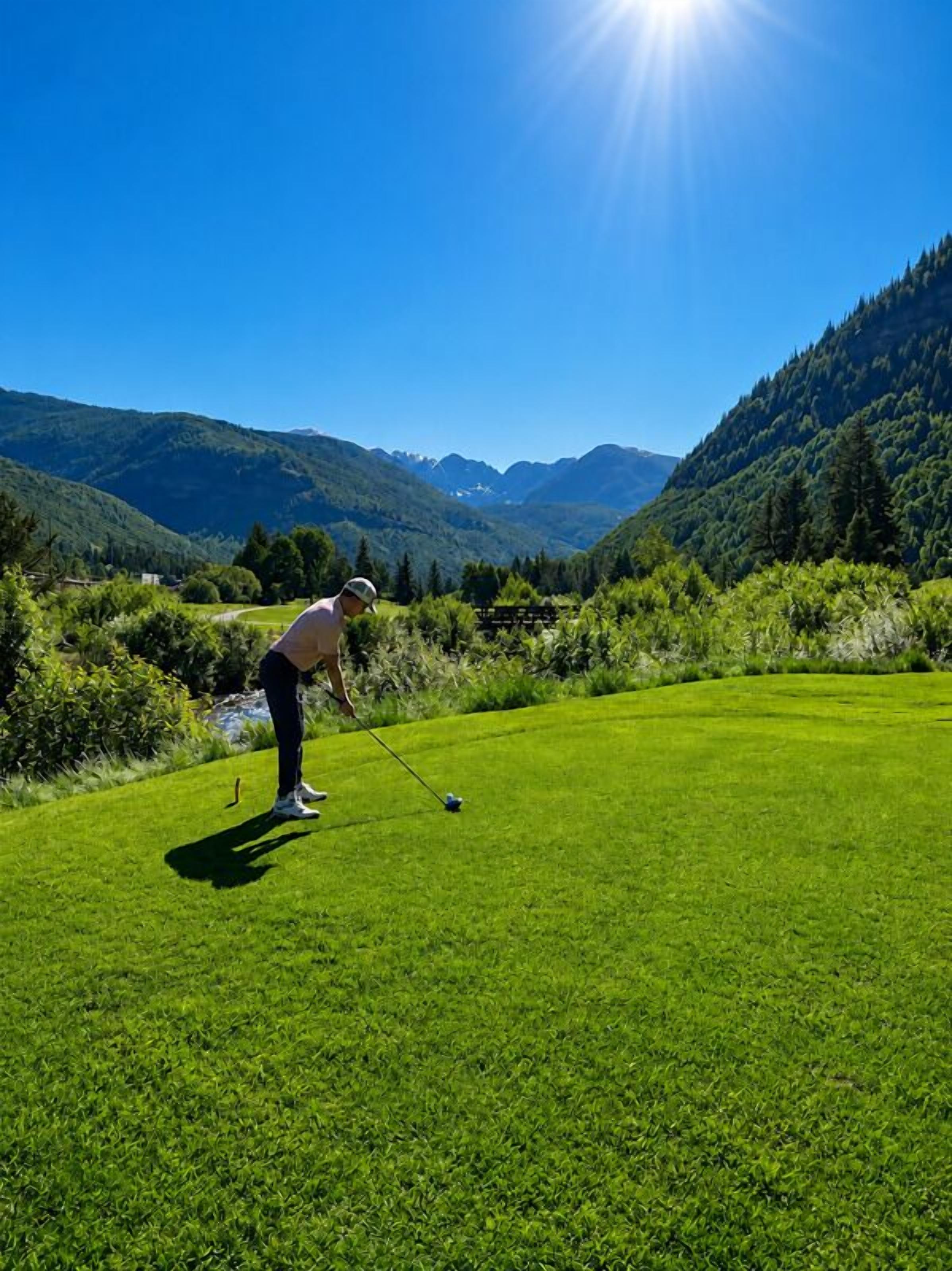 A person playing golf on a well-manicured green with a clear view of the surrounding mountains.