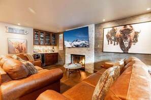 A cozy living room with leather sofas, a fireplace, and artwork on the walls.