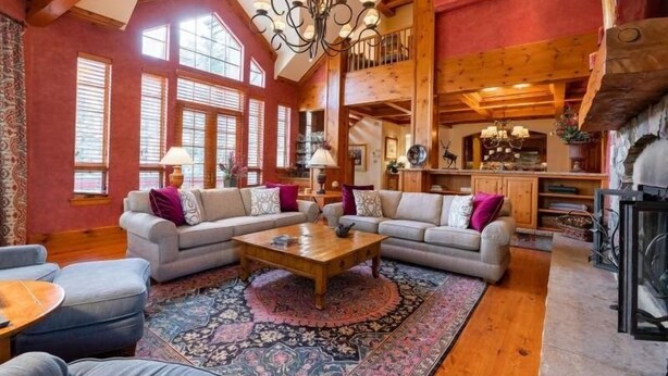 A spacious living room with a large wooden coffee table, two sofas, and a patterned rug.