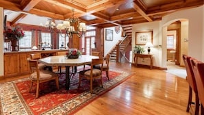 A spacious dining area with a wooden ceiling, a large round table, and several chairs.