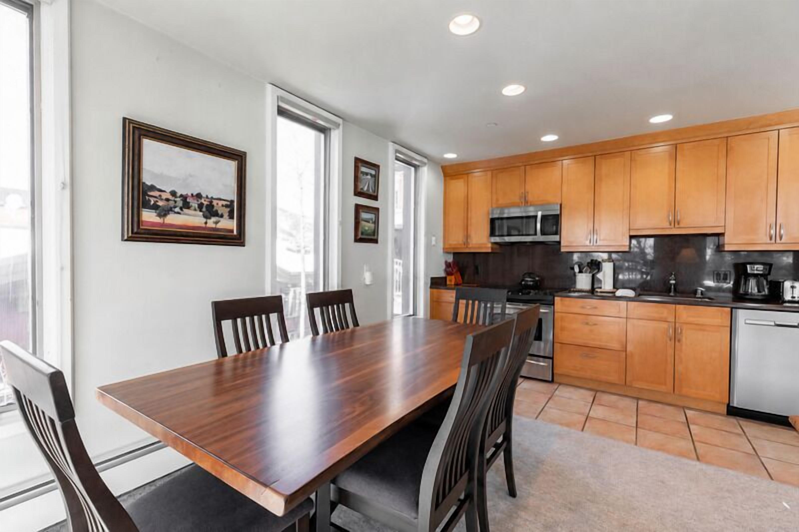 A modern kitchen with wooden cabinets, a large dining table, and chairs.